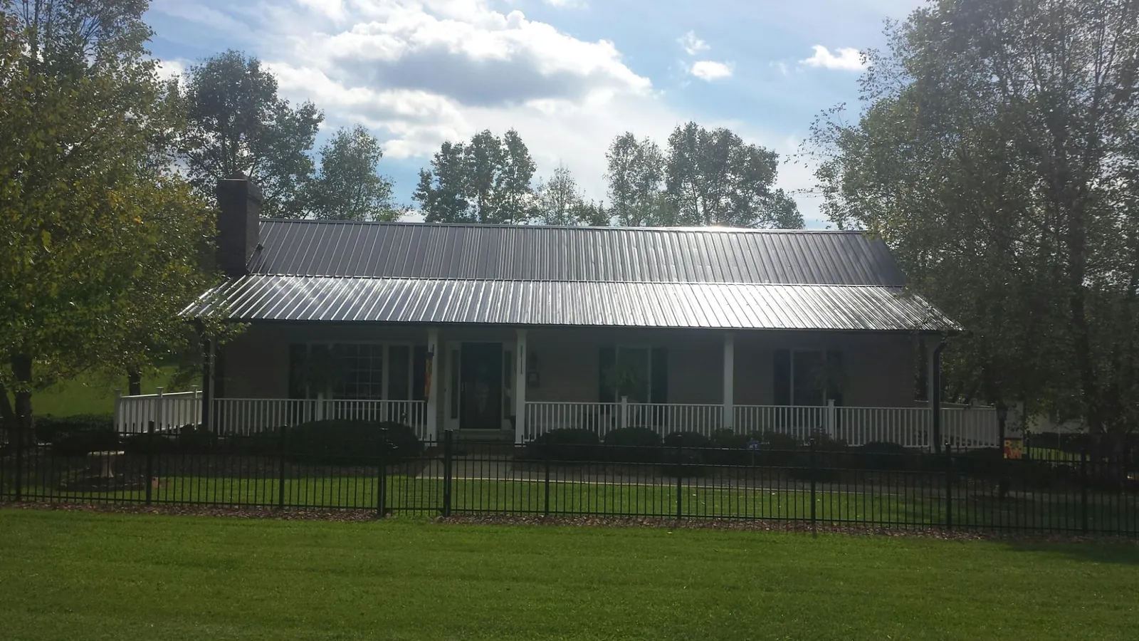 Gray metal roof on a brick ranch with a full width front porch — Gutter Guard Installation work by our crew in Dunlap